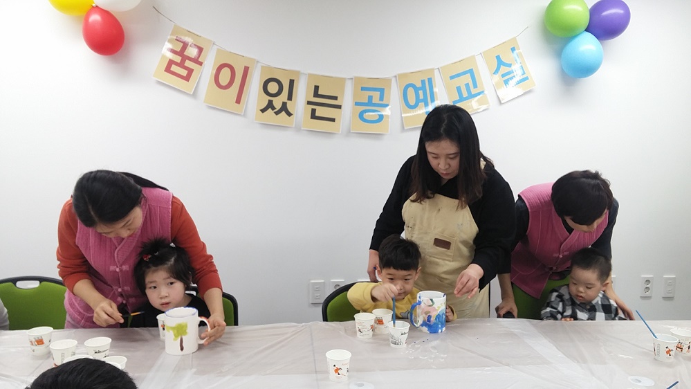 공예교실 강사와 어린이집 선생님들이 아이들에게 만드는 법을 알려주고 있다.