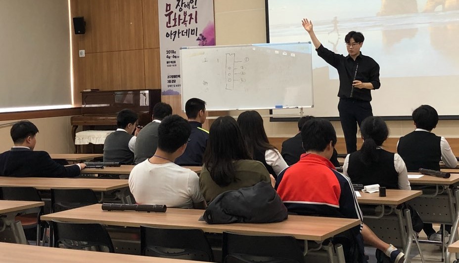 국악교실 강사가 수강생들에게 단소의 사용법을 알려주고 있는 모습