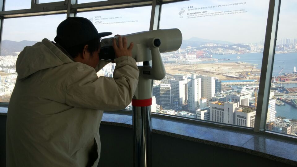 훈련생이 부산타워에서 망원경을 통해 바깥을 보고 있다.