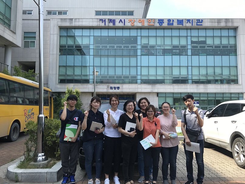 거제시 장애인종합복지관 앞에서 직원들이 화이팅 포즈로 서있다.