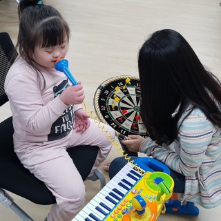 아동이 장난감 마이크를 만지며 노래를 부르는 듯한 모습을 보이고 있다.