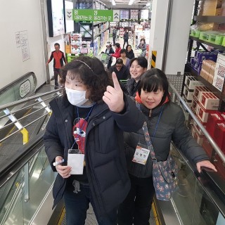 이용자들이 마트에서 무빙워크를 이용하여 위층으로 이동하고 있는 모습