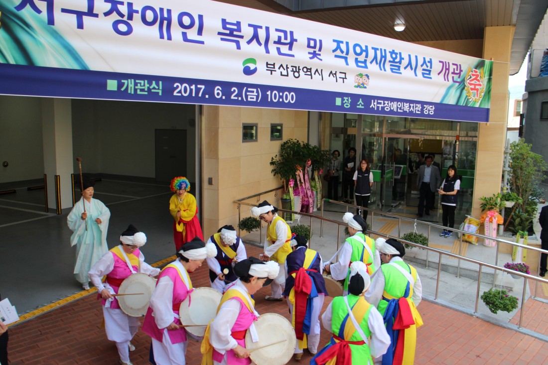 복지관 개관을 축하하는 공연이 복지관 정문에서 이루어지고 있는 사진