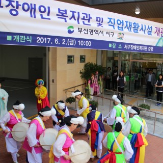 복지관 개관을 축하하는 공연이 복지관 정문에서 이루어지고 있는 사진