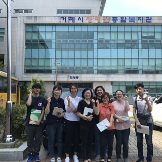 거제시 장애인종합복지관 앞에서 직원들이 화이팅 포즈로 서있다.